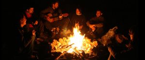 Friends sitting around campfire at night