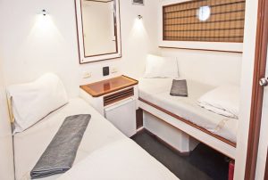 Twin boat bed mattresses in yacht cabin with wood paneling