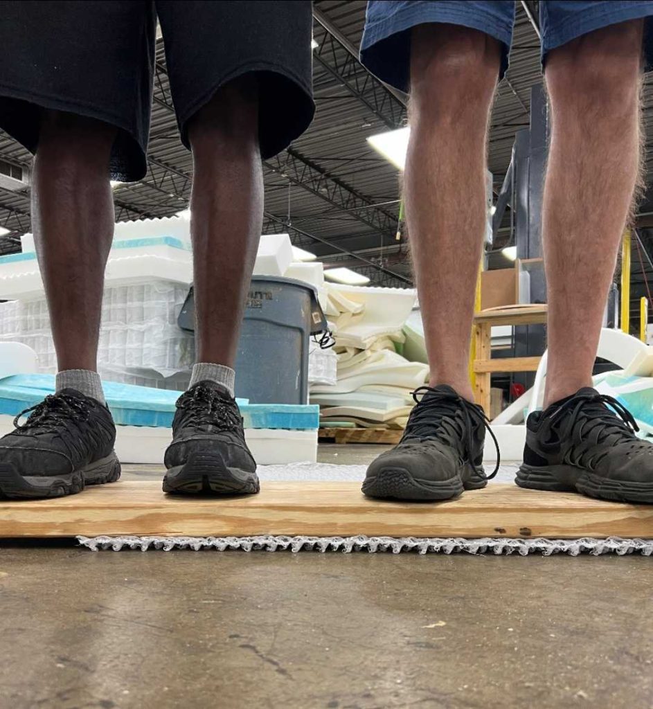 Two individuals standing on the moisture barrier showing it's durability